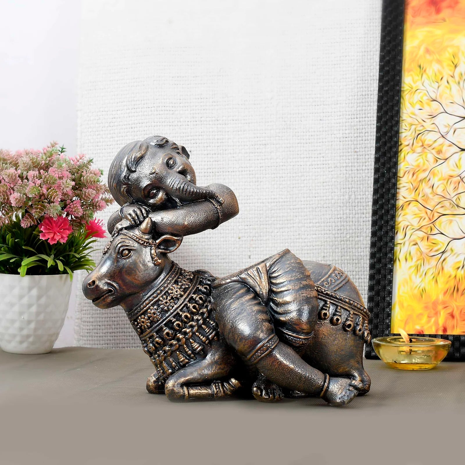 Antique-finish statue of Bal Ganesha resting on a decorated cow, ideal for home décor and gifting