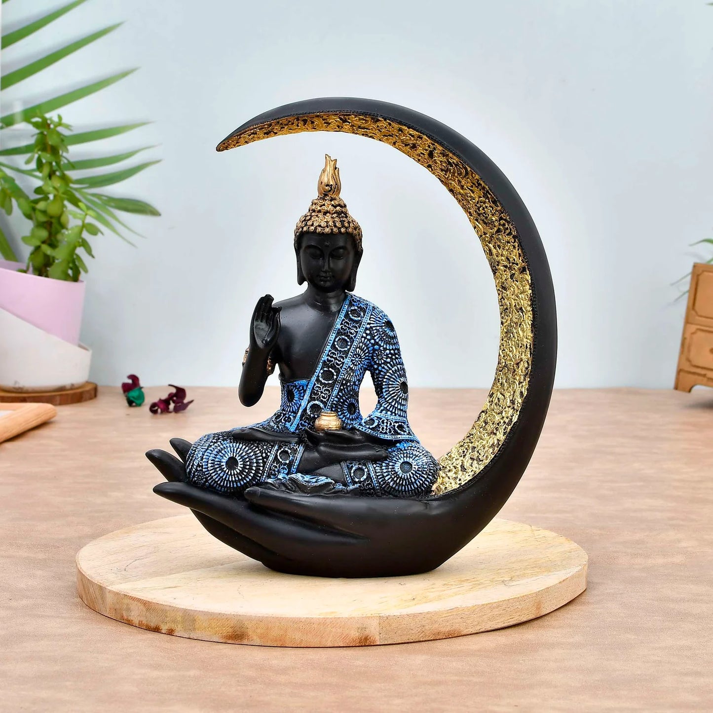 Decorative resin Buddha idol seated in a hand with a crescent moon backdrop