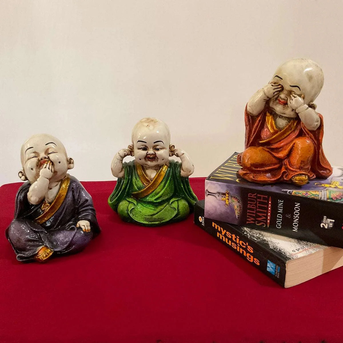 Set of three marble baby monk statues depicting see no evil, hear no evil, speak no evil concept in colorful robes